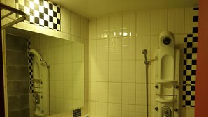 Un bagno con un lavandino bianco, uno specchio, una doccia e piastrelle a scacchi sulle pareti.