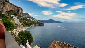 A coastal view with a cliff, buildings, and a boat on the water. - Il Sogno Costa d’Amalfi - Sea View Apartment (Conca dei Marini)