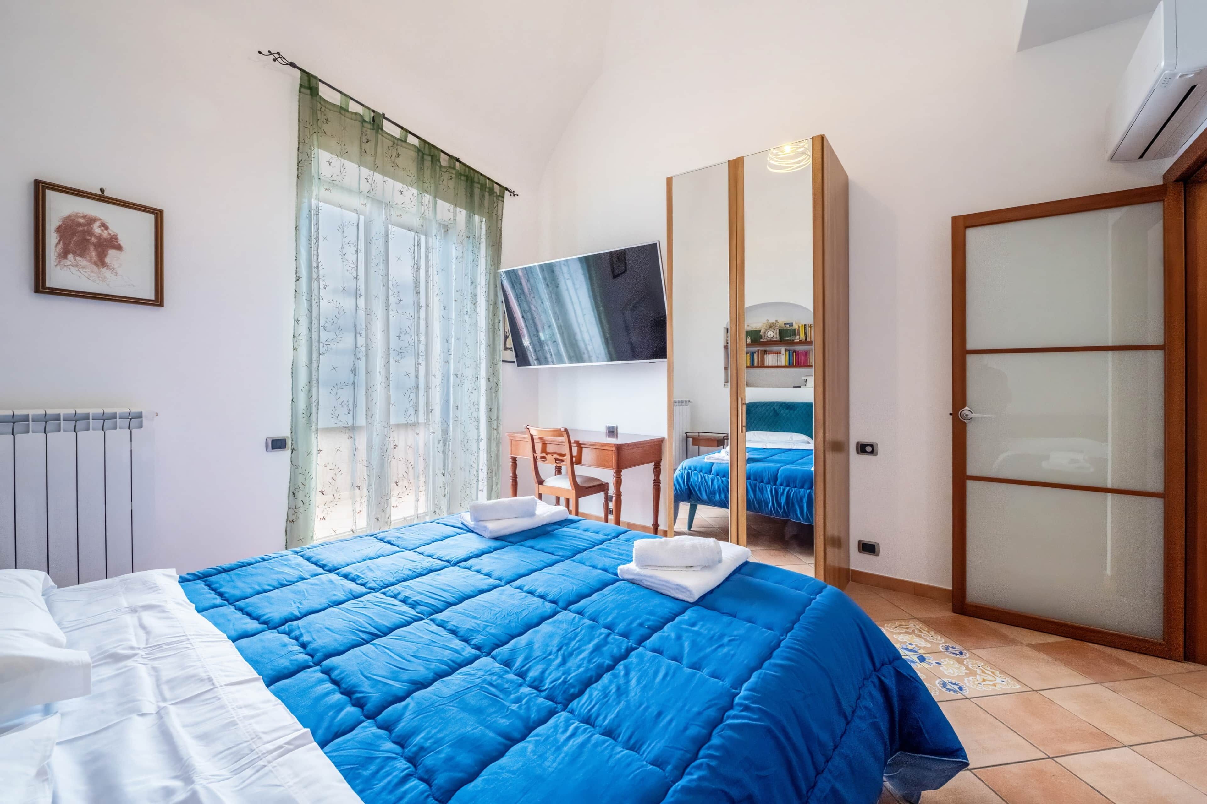 Une chambre à coucher comprenant un lit, un bureau, une chaise, une télévision et une armoire.