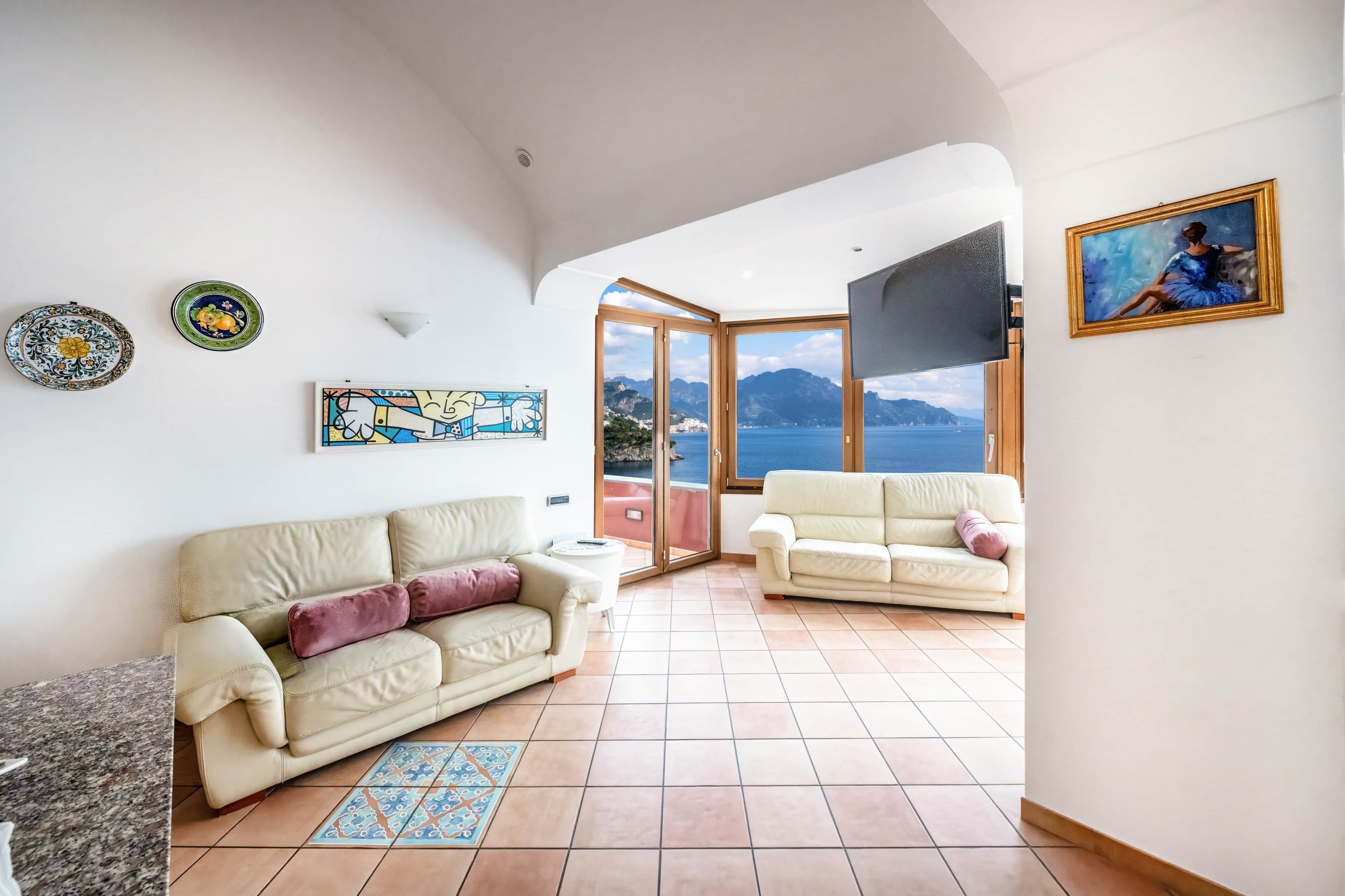 Ein Wohnzimmer mit zwei Sofas, einem Couchtisch, einem Fernseher und einem Gemälde an der Wand.