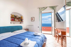 A bedroom with a bed, a bookshelf, a TV, and a balcony with a view. - Il Sogno Costa d’Amalfi - Sea View Apartment (Conca dei Marini)