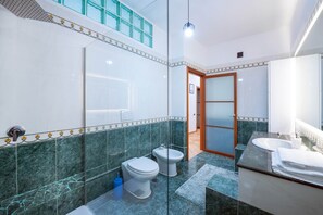 A modern bathroom with a glass partition, a shower, a toilet, a bidet, and a sink with a towel stack. - Il Sogno Costa d’Amalfi - Sea View Apartment (Conca dei Marini)
