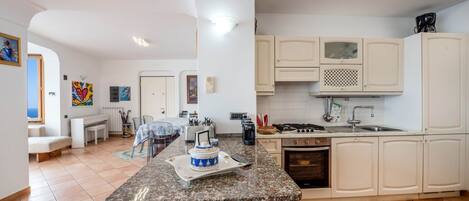 Une cuisine moderne dotée d’un plan de travail en granit, de meubles blancs, d’une cuisinière et d’un coin repas avec une table et des chaises.