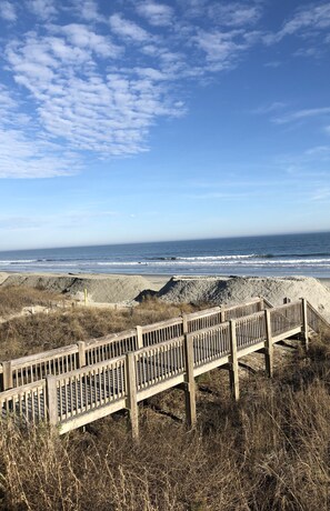 A wooden boardwalk leading to a beach with a clear sky and ocean in the background. - Come Relax At Barefoot Resort.  Golf course views from our first floor unit.    (North Myrtle Beach)