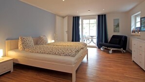 A bedroom with a bed, bedside table, and a chair. - Shell Whg. dolphin, Germany (Ostseebad Boltenhagen)
