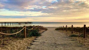 A paved pathway leading to a beach with a wooden pier in the background. - Shell Whg. dolphin, Germany (Ostseebad Boltenhagen)