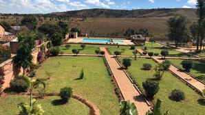 A landscaped garden with a swimming pool, pathways, and a view of distant hills.