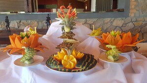 A table with fruit sculptures and a statue in the background.