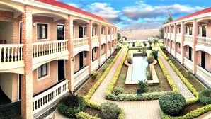A courtyard with a central water feature, surrounded by brick buildings with balconies.