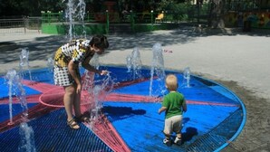 A woman and a child playing in a water fountain area with multiple water jets. - Apartments in front of the Park (Tbilisi)