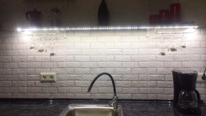 A kitchen with a white brick backsplash, a stainless steel sink, and a coffee maker. - Apartments in front of the Park (Tbilisi)