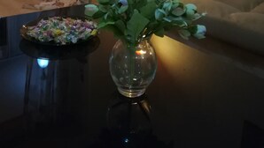 Ein Wohnzimmer mit einer Couch, einem Tisch mit Blumenvase und einer Stehlampe.