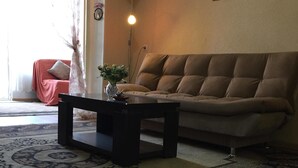 Ein Wohnzimmer mit einer Couch, einem Couchtisch, einer Lampe und einem Teppich.