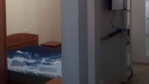 Huoneessa on sänky, työpöytä ja seinälle asennettu televisio.