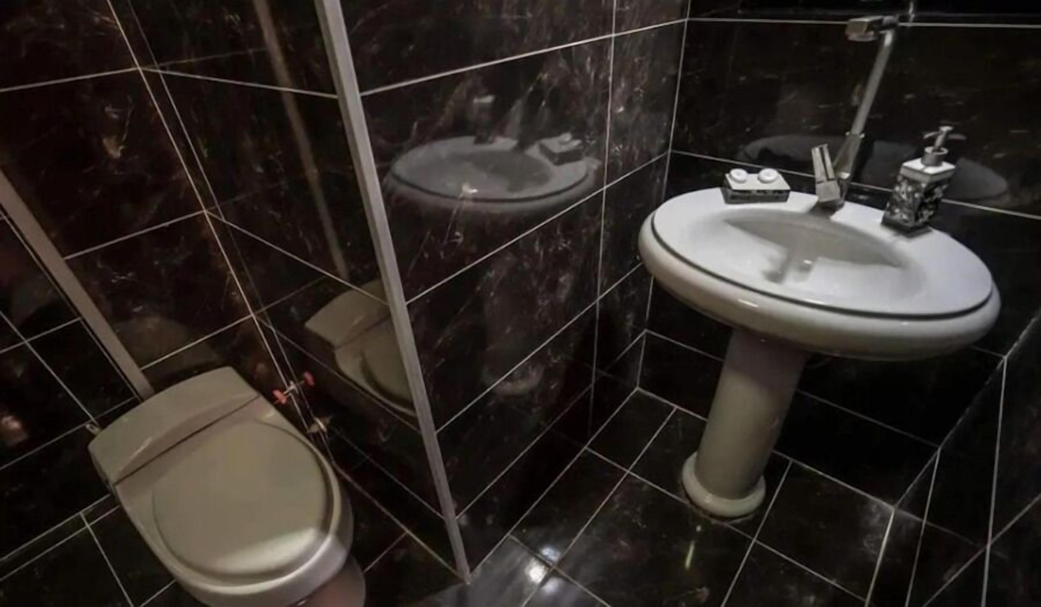 A bathroom with a toilet, sink, and mirror.