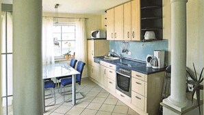 A kitchen with a dining table and chairs, a sink, a stove, and cabinets.