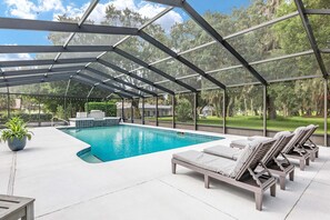 A covered outdoor swimming pool with lounge chairs and a potted plant.