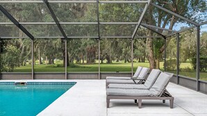 A covered outdoor pool area with lounge chairs and a view of a golf course. - Vacation Home With A Stunning View - 870 3 Bedroom Home by RedAwning (Inverness)