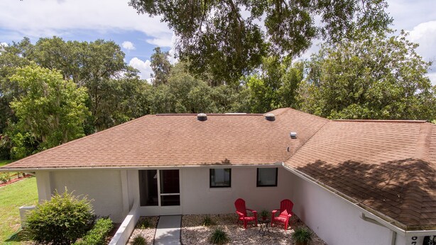 A single-story house with a red-tiled roof, a covered patio with red chairs, and a landscaped garden. - Vacation Home With A Stunning View - 870 3 Bedroom Home by RedAwning (Inverness)