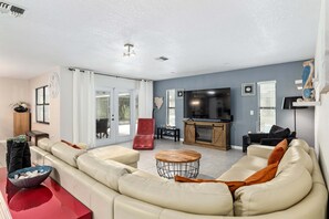 A modern living room with a sectional sofa, a red chair, a wooden coffee table, and a flat-screen TV. - Vacation Home With A Stunning View - 870 3 Bedroom Home by RedAwning (Inverness)