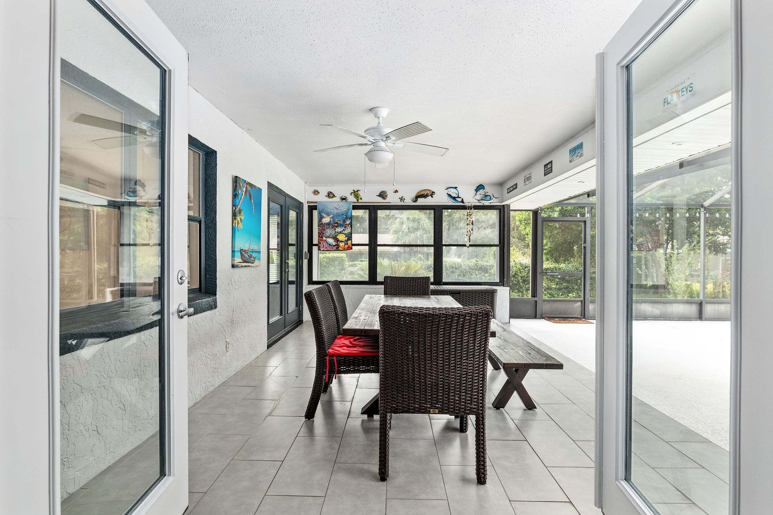 An open-plan dining area with a ceiling fan, large windows, and a view of the outdoors.