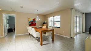 A spacious dining area with a wooden table and white chairs, a ceiling fan, and a large window providing natural light. - Vacation Home With A Stunning View - 870 3 Bedroom Home by RedAwning (Inverness)