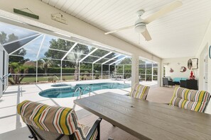 A covered outdoor pool area with a table and chairs, a hot tub, and a view of the surrounding greenery. - Family Villa Bettina - Recently Remodeled 2 Bedroom Home by RedAwning (Inverness)