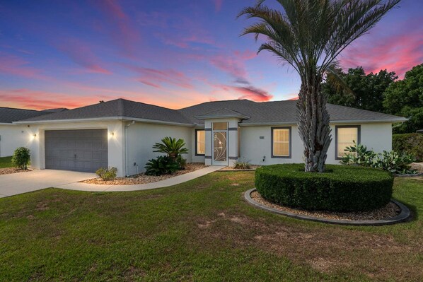 A single-story house with a garage, a well-maintained lawn, and a palm tree. - Family Villa Bettina - Recently Remodeled 2 Bedroom Home by RedAwning (Inverness)