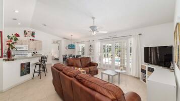 A modern living space with a brown leather sofa, a dining area, and a kitchen.
