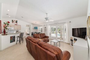 A modern living space with a brown leather sofa, a dining area, and a kitchen. - Family Villa Bettina - Recently Remodeled 2 Bedroom Home by RedAwning (Inverness)