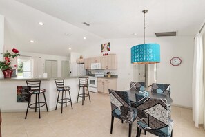 A modern kitchen with white cabinets, a central island, and bar stools. - Family Villa Bettina - Recently Remodeled 2 Bedroom Home by RedAwning (Inverness)