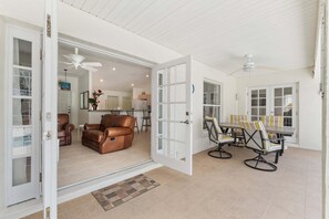 An open door leading to a living room with a brown leather sofa, a dining area with striped chairs, and a kitchen in the background. - Family Villa Bettina - Recently Remodeled 2 Bedroom Home by RedAwning (Inverness)
