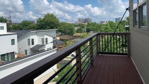 Een balkon met uitzicht op omliggende huizen en een heldere lucht.