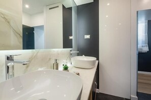 A modern bathroom with a large white sink, a mirror, and a dark accent wall.