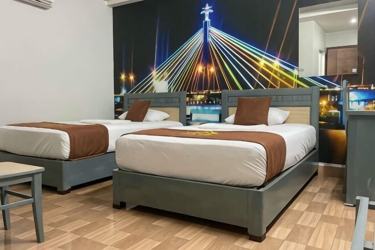 Habitación de hotel con dos camas, un escritorio y un mural con vistas a la ciudad.
