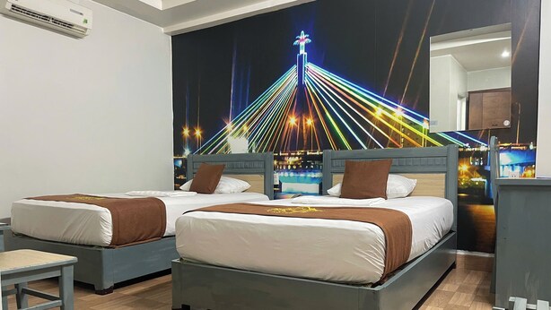 A hotel room with two beds, a nightstand, a chair, and a wall mural of a cityscape at night. - Cozi Hotel (Hai Phong)