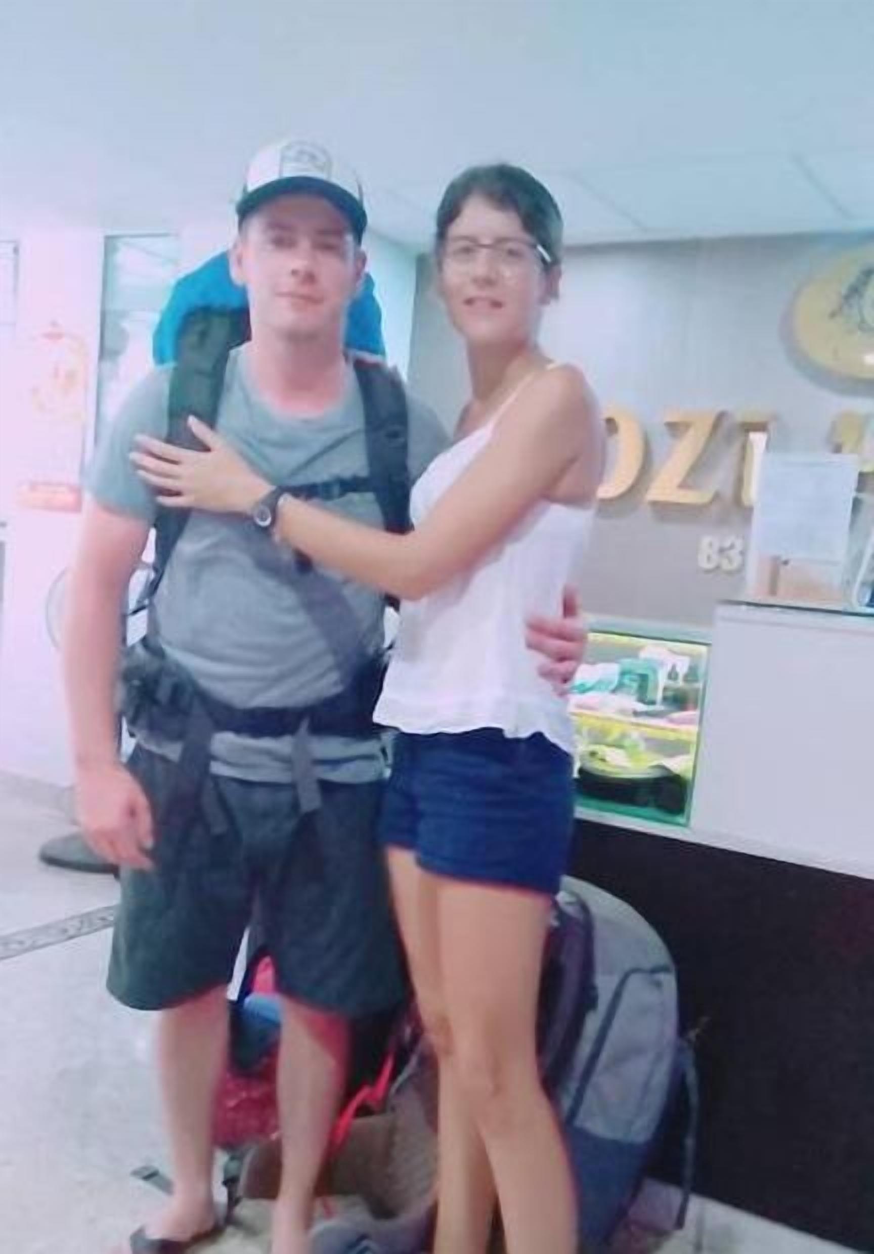 A man and a woman standing in a room with a reception desk and a clock on the wall.
