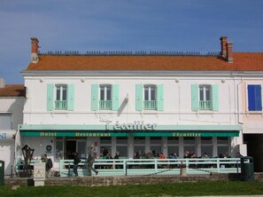 Ein weißes Gebäude mit grünen Fensterläden und einem Schild mit der Aufschrift 'Hotel Restaurant'.