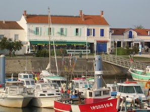A harbor with several boats docked, a building with a sign reading "Hotel Restaurant L'Ecaille", and a bridge leading to another building with a sign "Le Piano Bleu". - Hôtel Restaurant L'Ecailler (Saint-Pierre-d'Oleron)