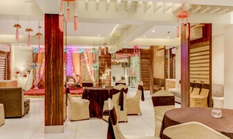 A hotel lobby with a central seating area, a reception desk, and a decorative wall with hanging ornaments.