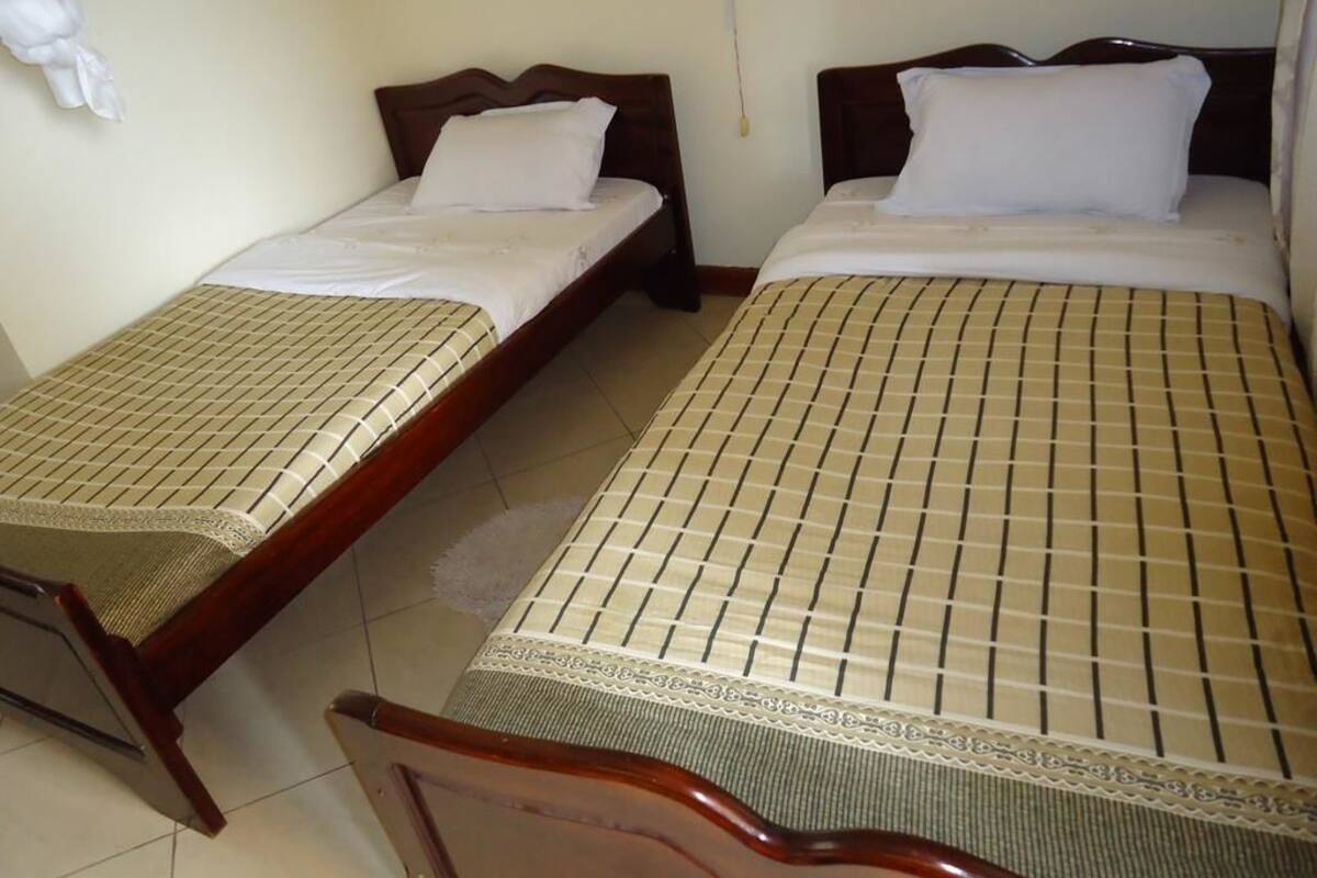 Two single beds with wooden frames and headboards, each with a patterned bedspread and white pillows.