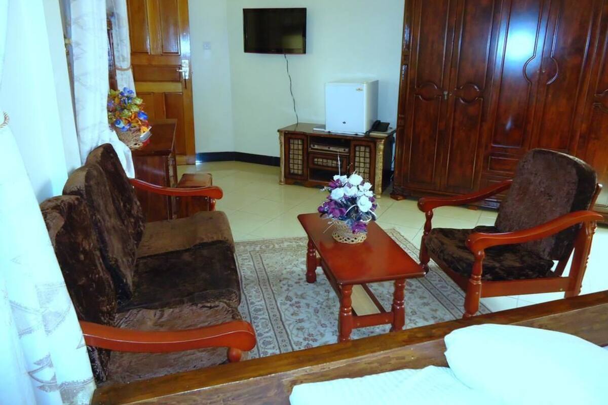 A living room with a sofa, armchairs, a coffee table, a television, and a cabinet.