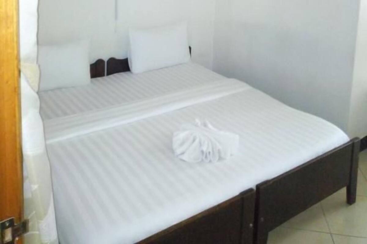 A single bed with a white bedspread and a white canopy.