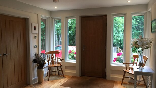 Una habitación amplia con ventanas grandes, una puerta de madera y suelo de madera.