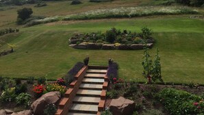 Un jardín bien cuidado con un sendero de piedra que lleva a una cama de flores circular rodeada por un borde de ladrillo.