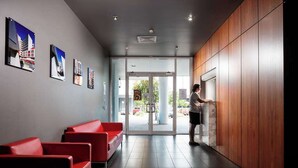 Un espace d’accueil avec un mur en bois, des sièges rouges et des tableaux encadrés accrochés au mur.
