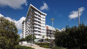 Un hôtel à plusieurs étages, doté de balcons, d’une antenne parabolique et surplombant un ciel d’un bleu limpide.