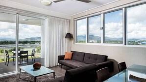 Un salon moderne avec un canapé, une table basse et une vue sur les montagnes grâce à de grandes fenêtres.