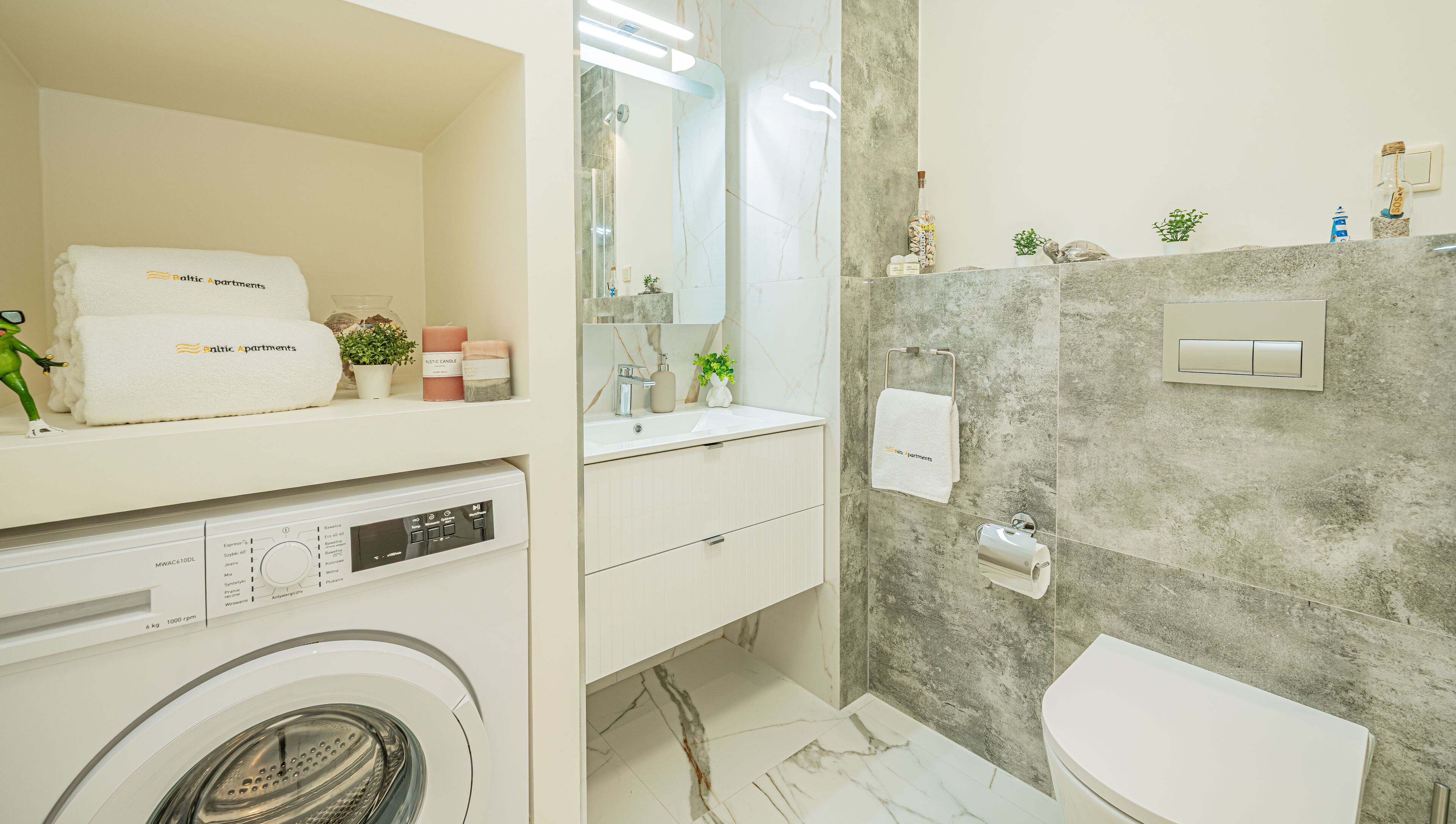 A modern bathroom with a washing machine, a sink, a mirror, and a toilet.