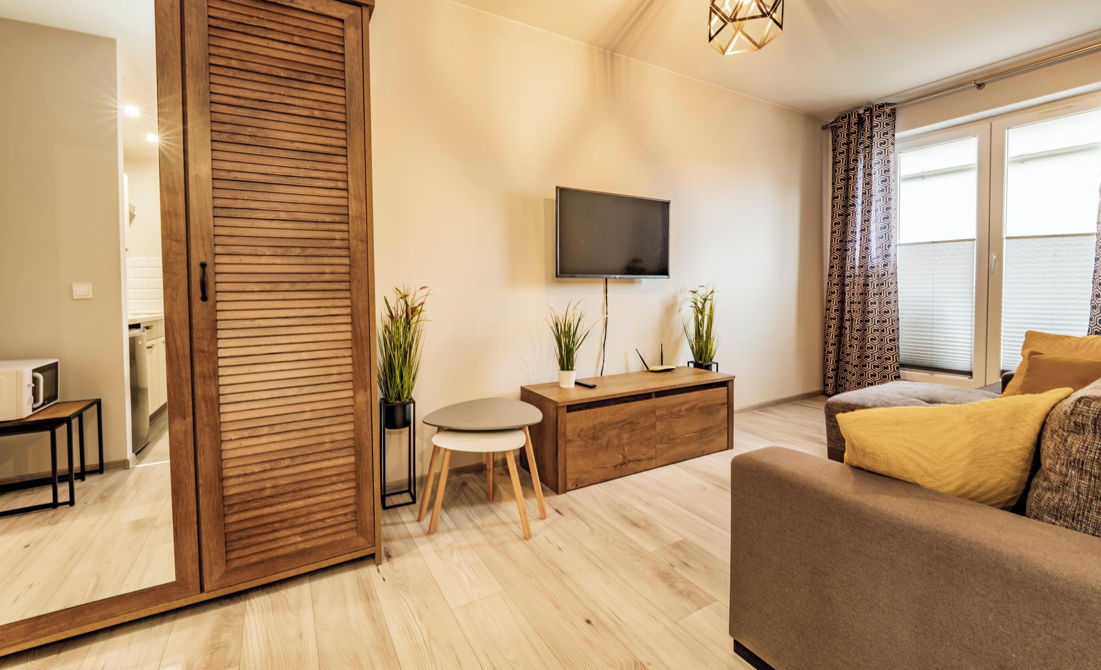 Uma sala de estar moderna com porta de madeira deslizante, televisão de tela plana, sofá, mesa de centro e plantas em vasos.